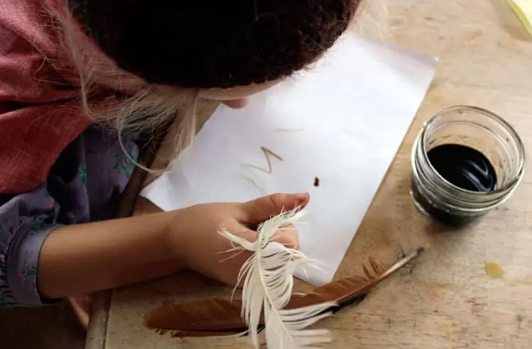 A child drawing and writing with black walnut ink