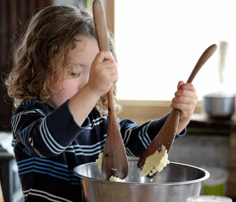 A child washing and pressing it with wooden spoons. 