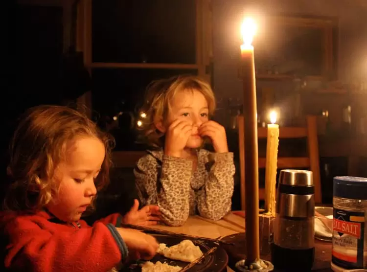 Kids sitting at a candlelit table. 