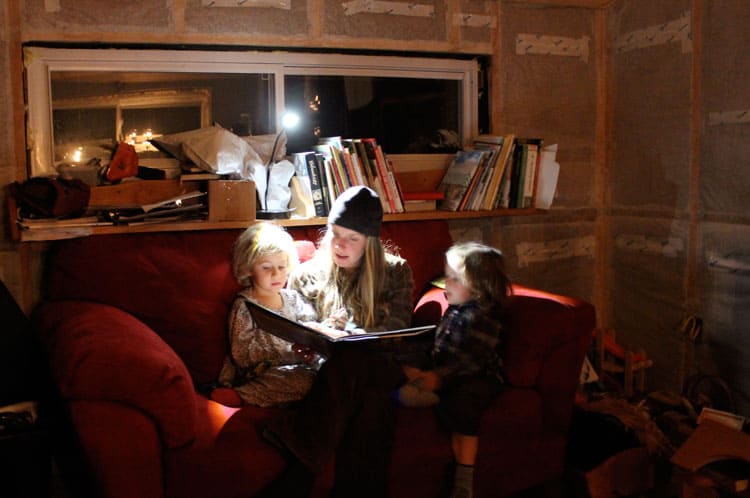 A woman reading 2 children a story with solar lamp. 