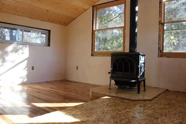 living room of an off-the-grid tiny house with hardwood floors and a wood stove