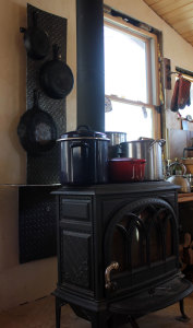 We make best use of space by hanging cast iron skillets on our homestead woodstove's heat shield, and keep pots of water on the stove to heat. | Homestead Honey