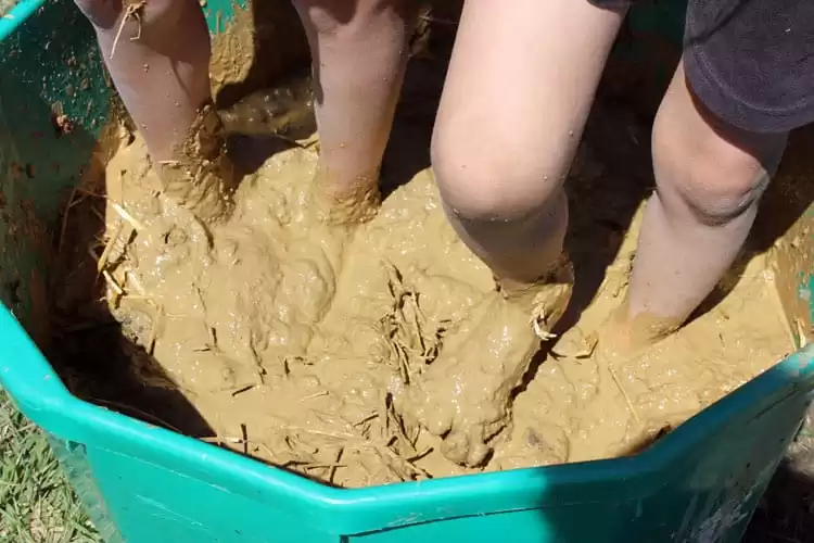 Kids help mix earthen plaster to spread on our outdoor pizza oven | Homestead Honey