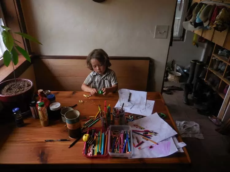 a small boy doing his homework at a built in bench table in a tiny house 