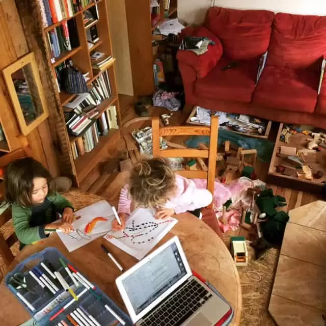 two kids drawing pictures at the living room table of a tiny house | Homestead Honey