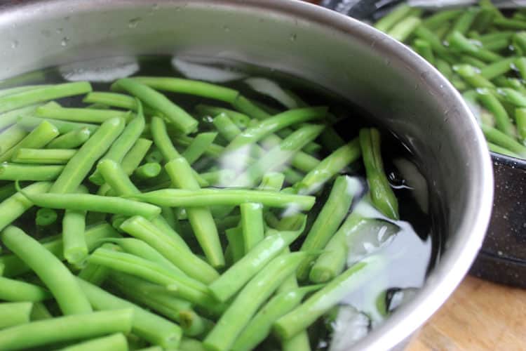 Plunging green beans in ice cold water to blanche before freezing