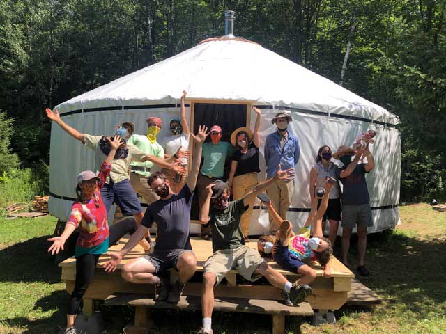 A crew of hardworking people celebrates at the end of a yurt raising in Central Vermont
